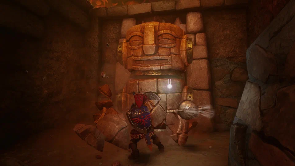 Adult Link in the red Goron Tunic with the Hylian Shield swinging the Megaton Hammer into a giant carved stone Goron-face statue blocking a doorway, chunks of rock flying, in a red-lit cavern