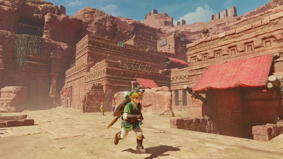 Adult Link running through Gerudo's Fortress: terraced red sandstone buildings with stepped geometric carvings, red canvas awnings, wooden watchtowers on the cliff tops, and two Gerudo guards in purple and yellow in the background