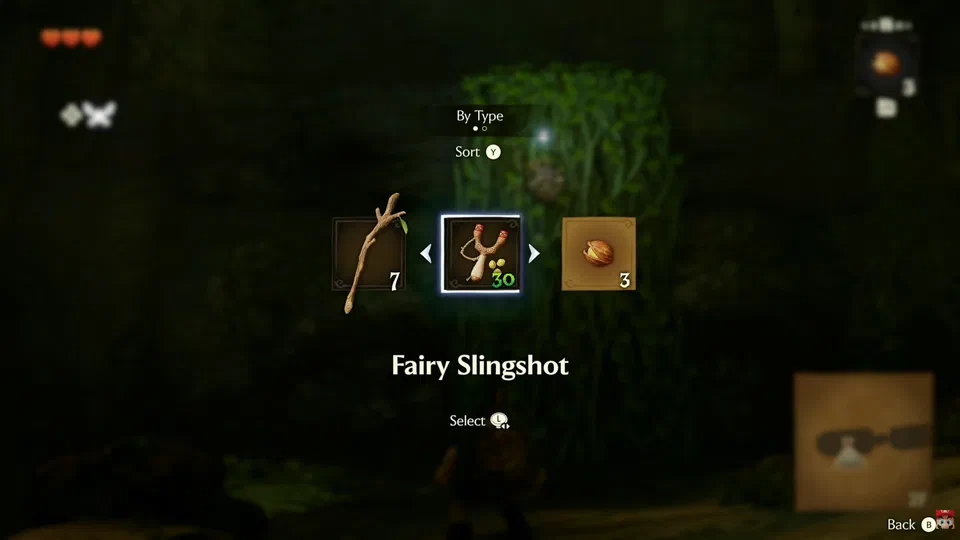 Quick item swap overlay over a blurred dungeon background: a horizontal carousel showing Deku Stick, Fairy Slingshot (selected) and Deku Nuts, with a Sort (Y) option labeled By Type